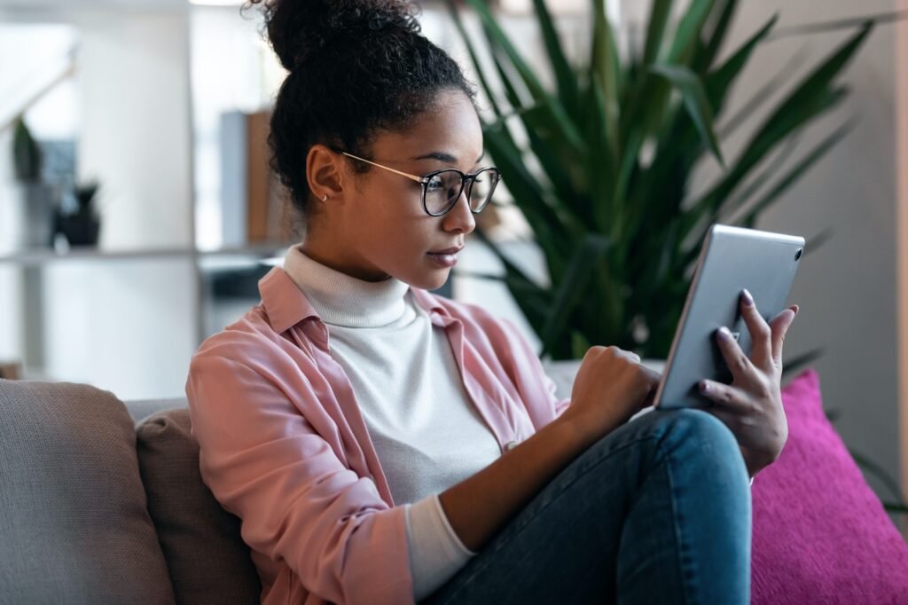 Beautiful young entrepreneur woman using her digital tablet while sitting on couch in the office.